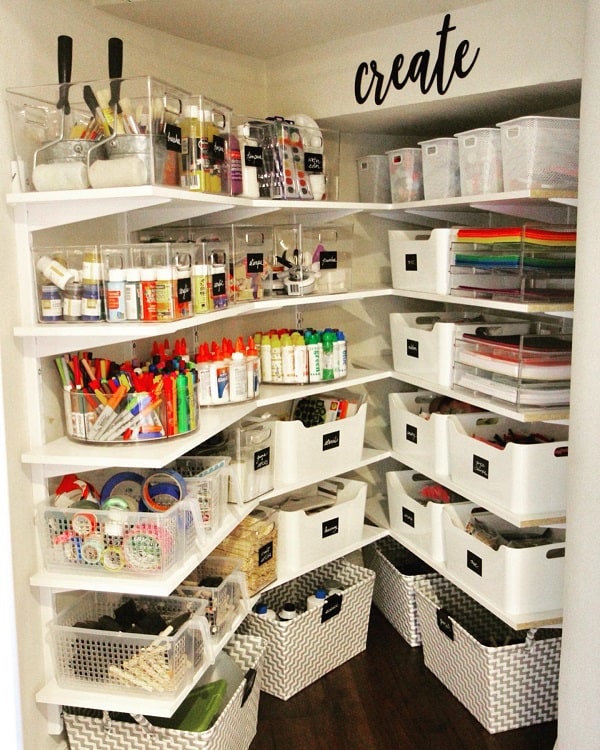 Craft room with organized shelves filled with art supplies, baskets, and bins under a "create" sign