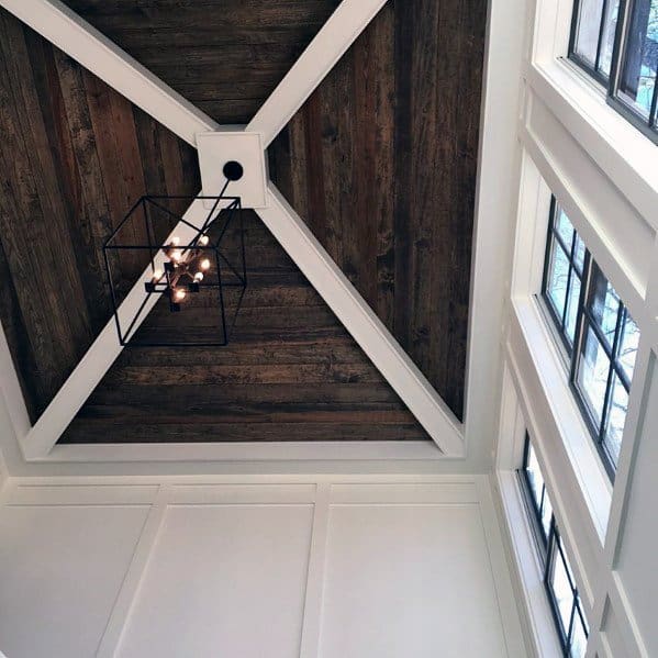 Dark wood ceiling with white beams in an X-pattern and a modern geometric pendant light.