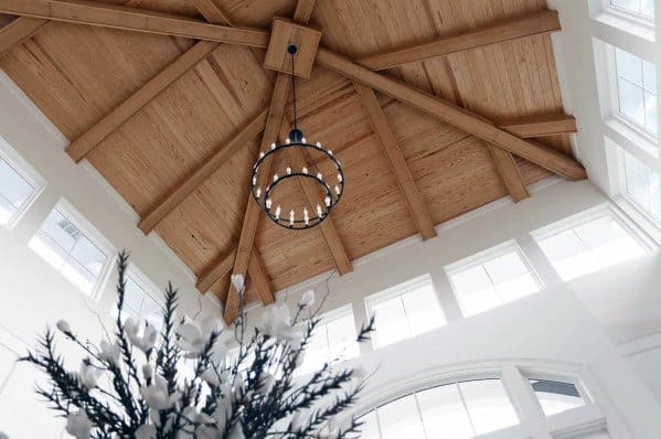 Vaulted wood ceiling with exposed beams, circular chandelier, and surrounding windows.