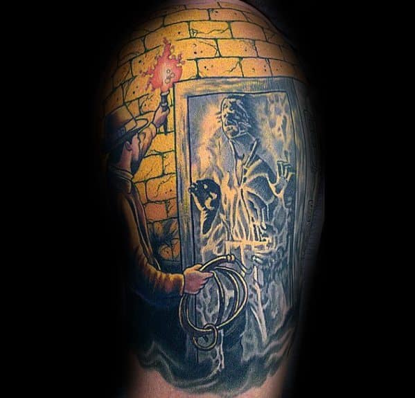 Indiana Jones tattoo depicting a torch-lit scene of Indy discovering an ancient figure encased in a mystical stone doorway.