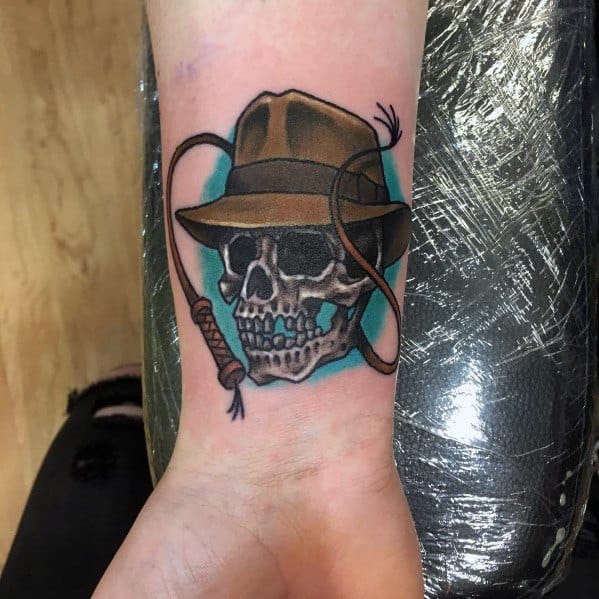 Indiana Jones-inspired tattoo featuring a skull wearing his iconic fedora, with a coiled whip for an adventurous, rugged design.