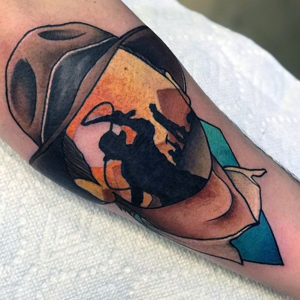 Creative Indiana Jones tattoo blending his iconic fedora with a desert adventure scene, featuring a whip-wielding silhouette.