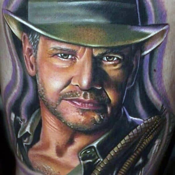 Highly detailed Indiana Jones tattoo showcasing his intense gaze, iconic fedora, and whip, with realistic shading and depth.
