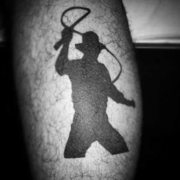 Bold black Indiana Jones silhouette tattoo showing him mid-action, cracking his iconic whip in a dynamic pose.