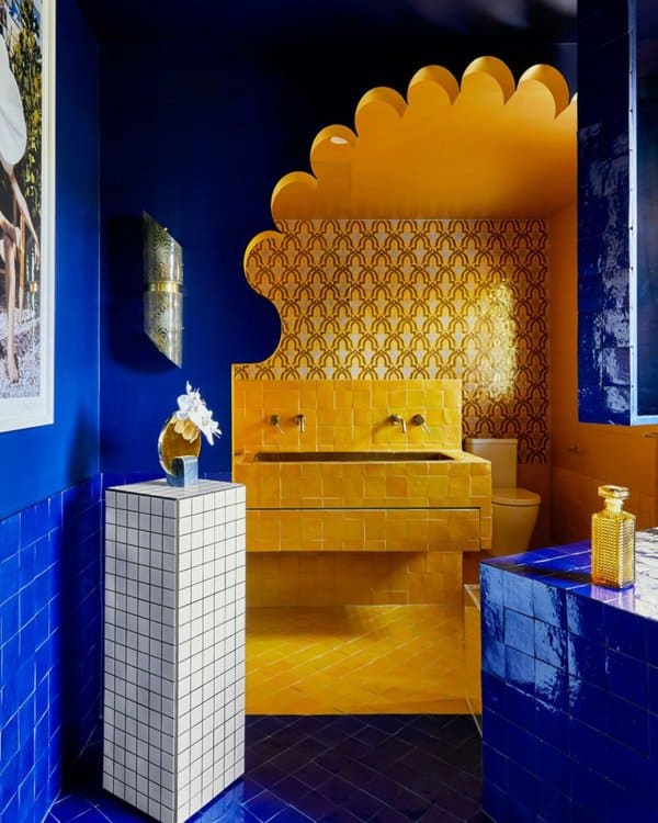 Bathroom featuring deep cobalt walls, vivid yellow tiles with a scalloped arch, and gold fixtures for a stunning contrast.