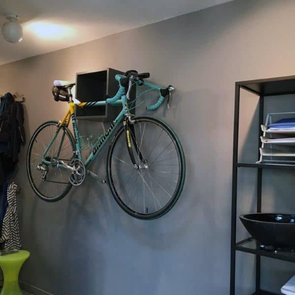 A sleek indoor bicycle storage solution featuring a wall-mounted black box shelf that securely holds the bike horizontally in a modern room.