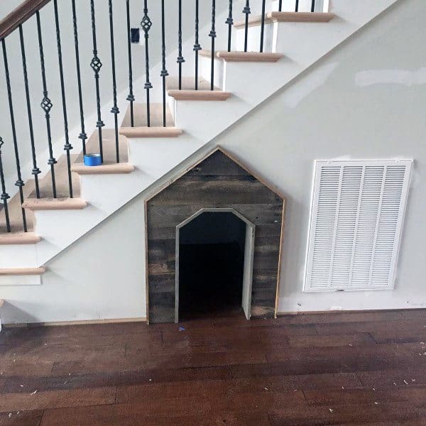 Dog house seamlessly built into the wall beneath a staircase