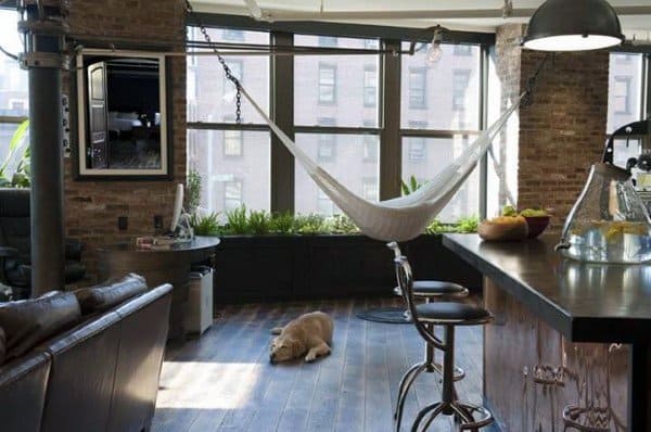 Hammock in a modern loft with exposed brick walls, large windows, and a cozy living space.