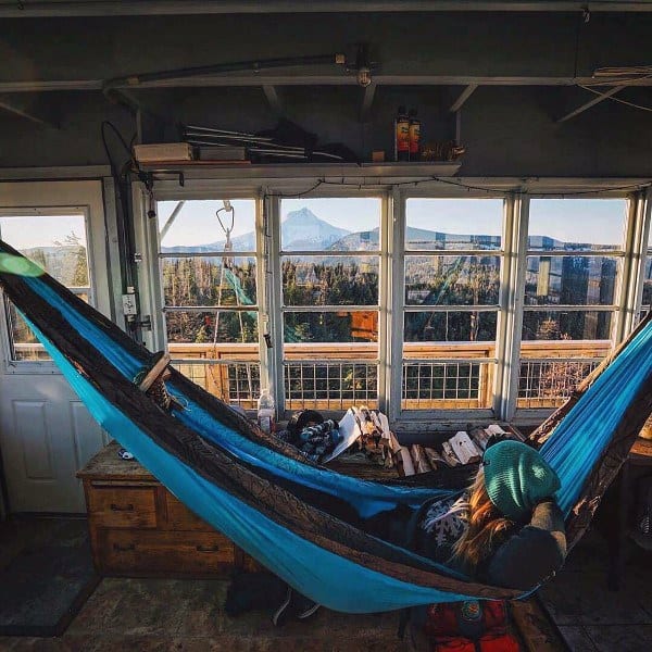 Hammock in a modern loft with exposed brick walls, large windows, and a cozy living space.