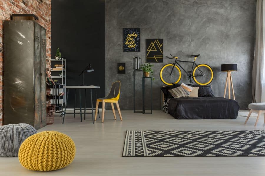 Industrial-style bedroom with concrete wall, wall-mounted bike, and yellow accents.