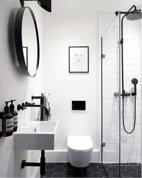 Minimalist bathroom with white round mirror, sink, toilet, and shower in black and white decor