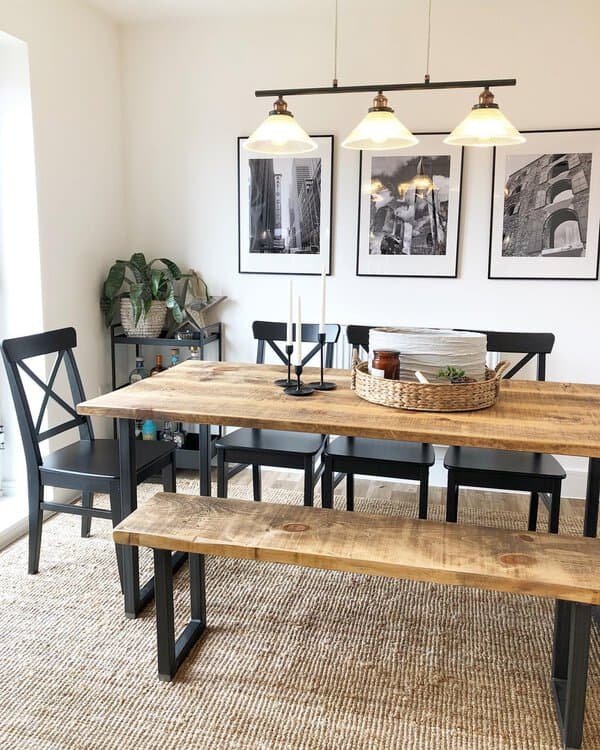 Industrial-inspired boho dining room with wooden table, black chairs, and vintage lighting.