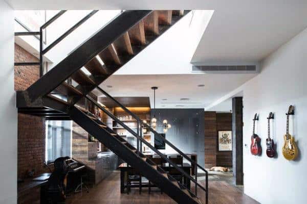 Industrial interior with metal staircase, brick walls, wooden accents, and guitars on display.