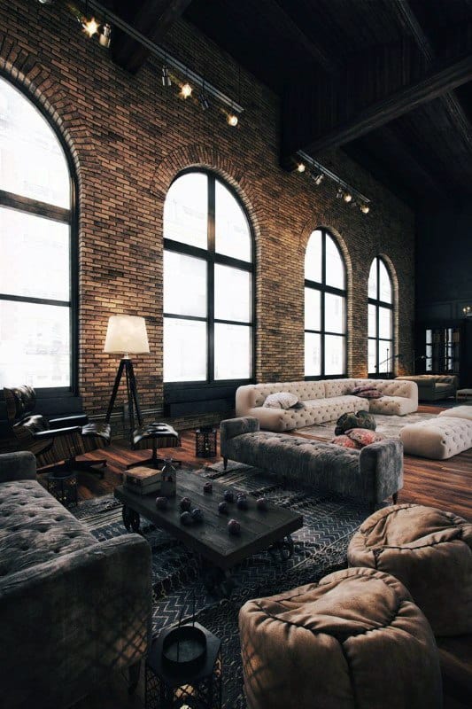 Cozy industrial living room with brick walls, arched windows, and tufted sofas.