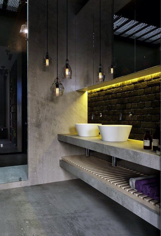 Industrial bathroom with concrete finishes, vessel sinks, and hanging pendant lights.