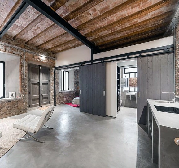Industrial loft with exposed beams, concrete floors, and sliding barn-style doors.
