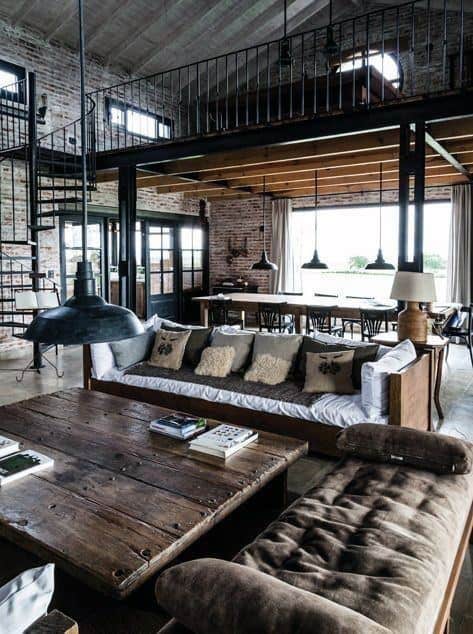 Rustic industrial living space with exposed brick walls, wooden furniture, and a spiral staircase.