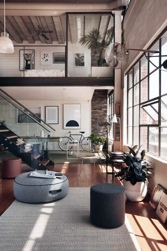 Modern industrial loft with large windows, mezzanine, and sleek minimalist decor.