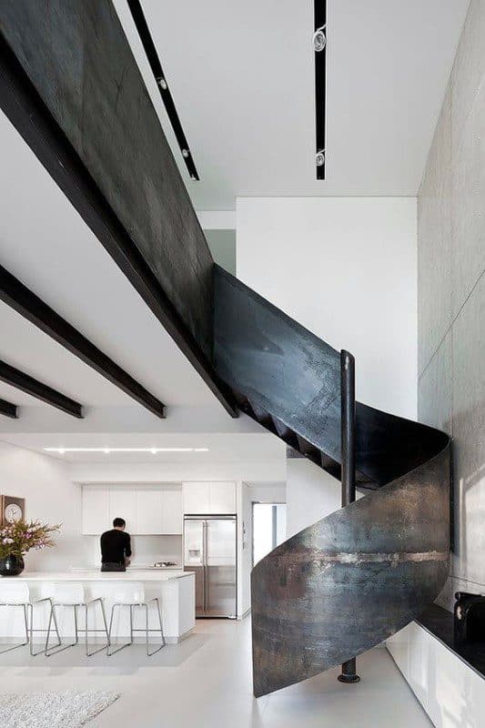 Minimalist interior with a black spiral staircase and modern white kitchen.