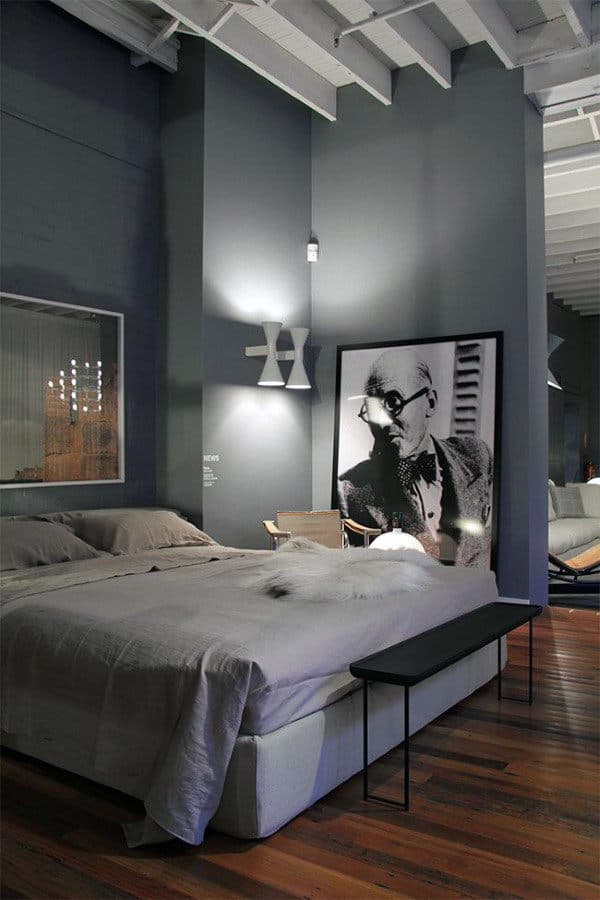 Modern bedroom with gray walls, large bed, and a framed monochrome portrait