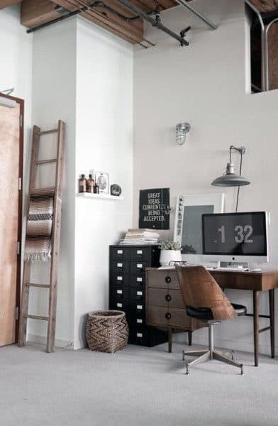 Minimalist home office with a wooden desk, chair, ladder, shelves, and a vintage cabinet decorated in neutral tones