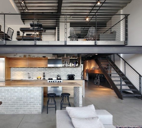 Industrial loft with open kitchen, brick accents, mezzanine, and metal staircase.