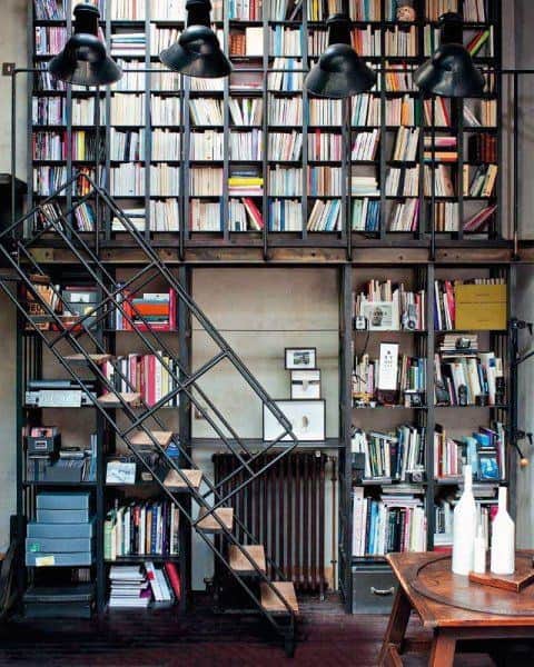 Loft library with tall bookshelves, a ladder, and stylish lighting above; cozy area with books and decor for library lovers