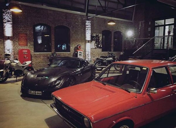A stylish industrial workshop garage featuring classic and modern vehicles with a rustic ambiance.