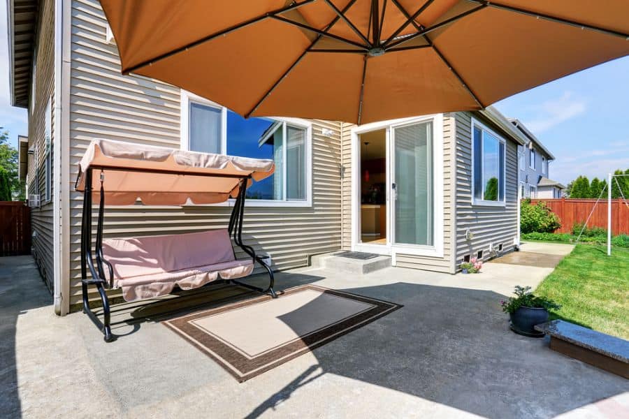 concrete patio with orange umbrella and swing seat