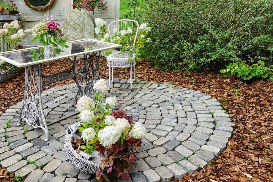 small paver stone patio with glass table and white chair
