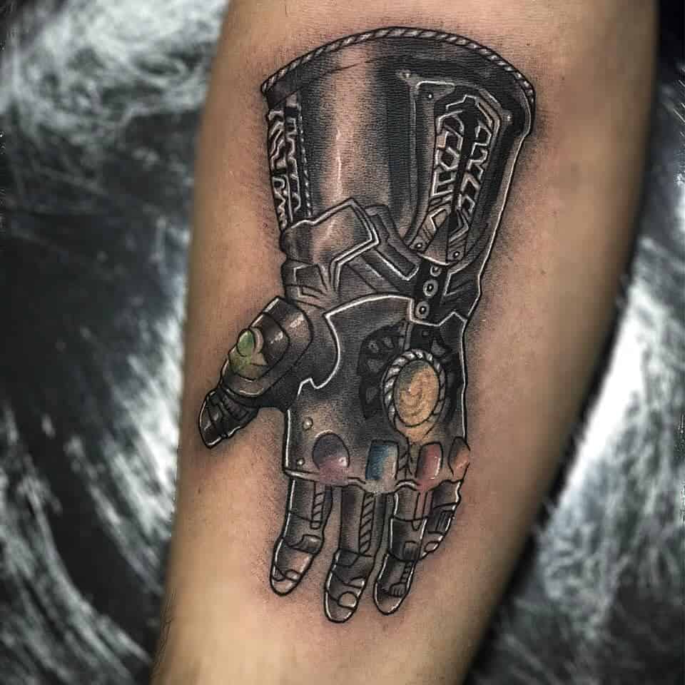 Detailed black and grey tattoo of Thanos' Infinity Gauntlet, featuring intricate shading and glowing Infinity Stones.