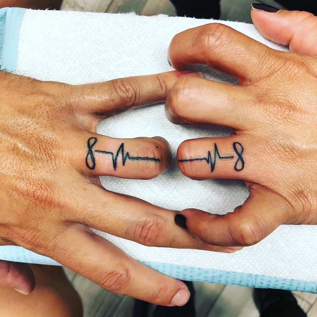 Matching wedding ring tattoos featuring a heartbeat line and the number 8, symbolizing infinity or eternal love