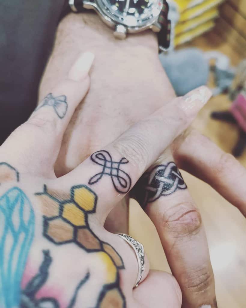 Matching wedding ring tattoos featuring intertwined loops and a Celtic knot design, symbolizing unity and connection