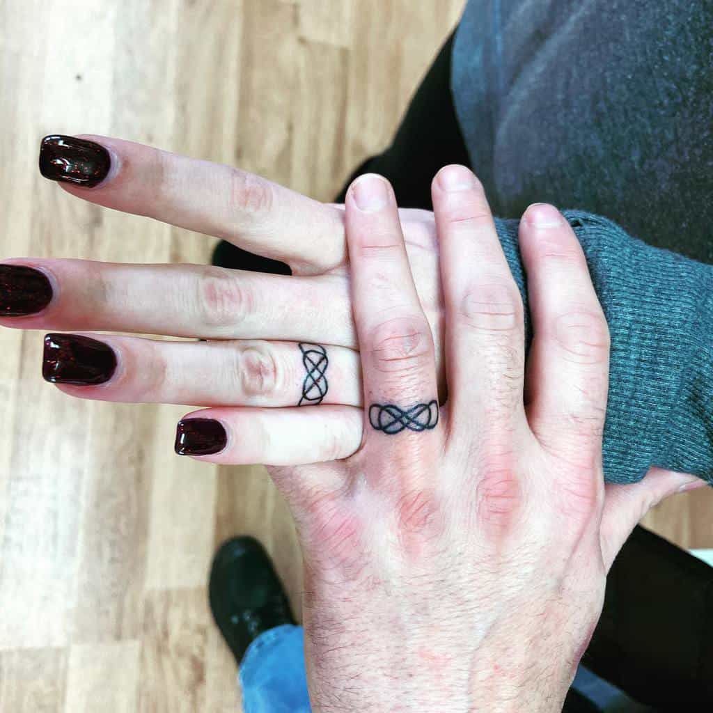 Matching wedding ring infinity symbol tattoos on the fingers, symbolizing eternal connection
