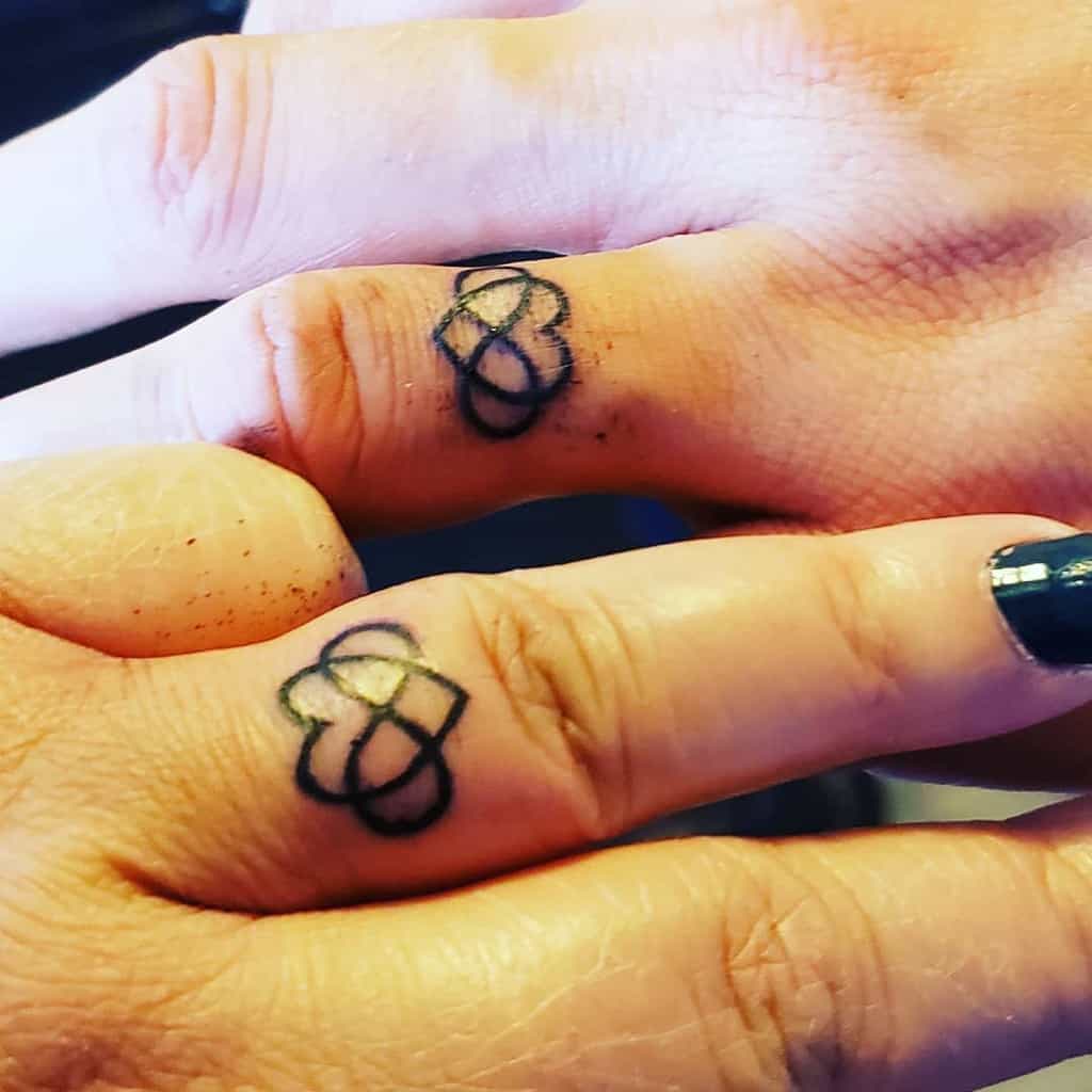 Matching wedding ring tattoos featuring intertwined hearts and infinity, symbolizing love and unity
