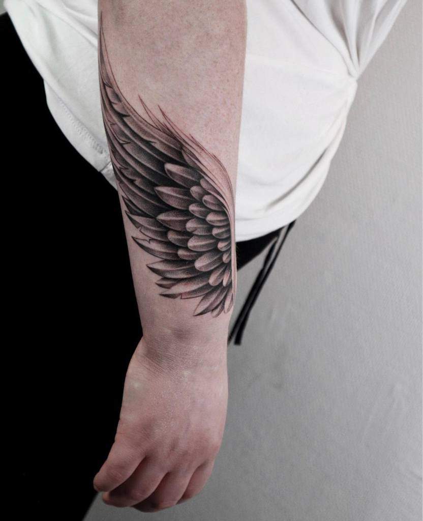 Tattoo of a detailed black and gray angel wing with intricate shadings