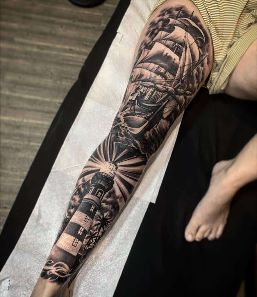 Leg sleeve tattoo of a lighthouse and sailing ship with ocean, clouds and palm trees