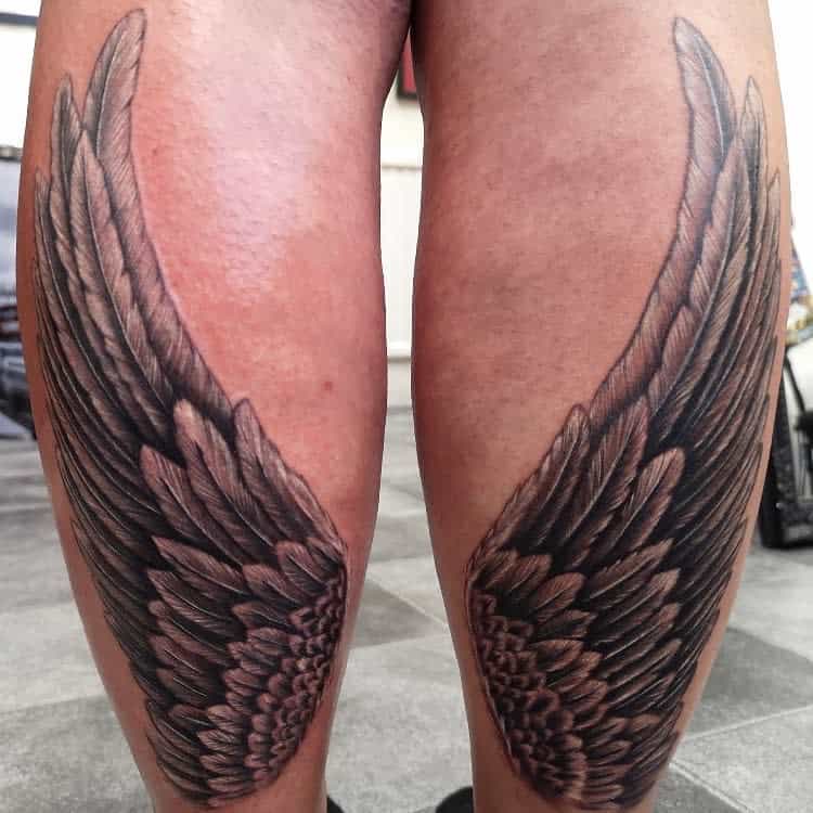 Detailed angel wings tattoos with intricate feathering and shading, creating a bold and symmetrical design