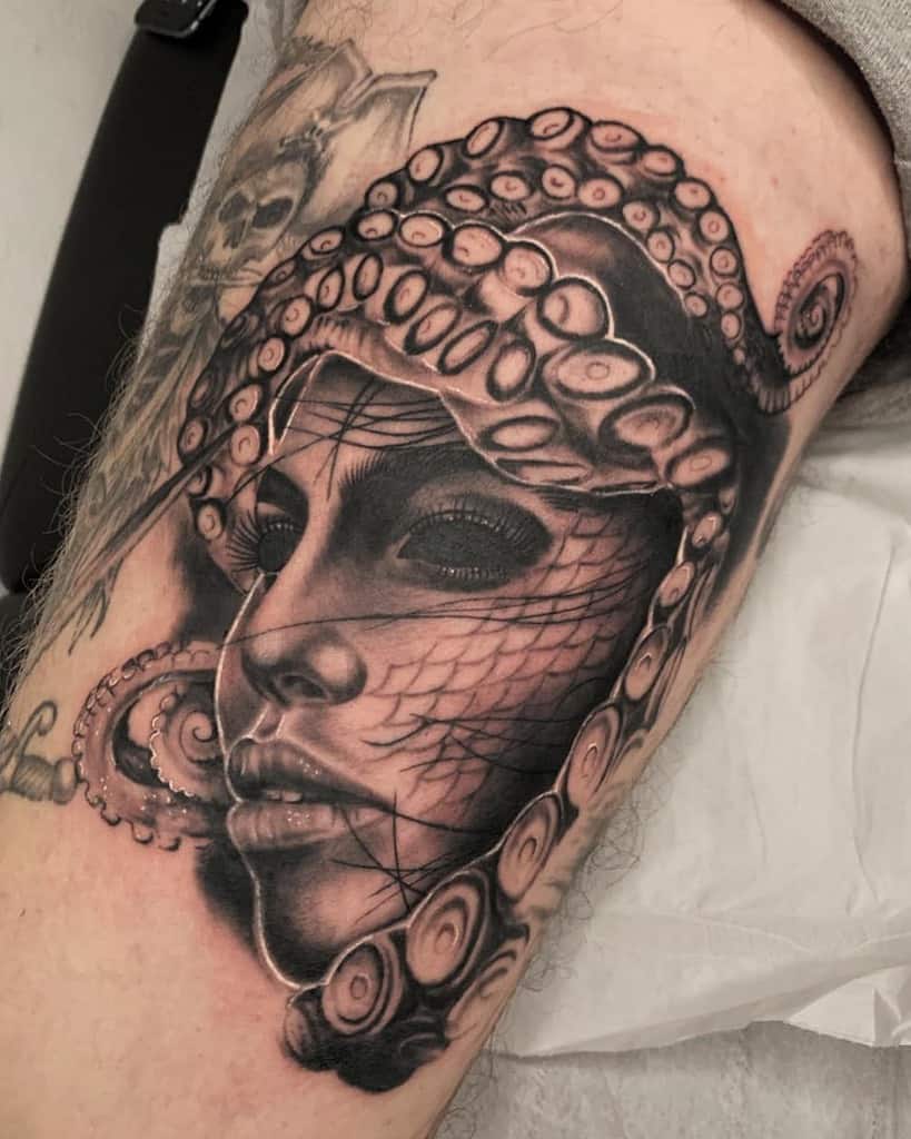 Black and grey tattoo of a woman's face merging with octopus tentacles, featuring intricate shading, net-like details, and a surreal oceanic theme.