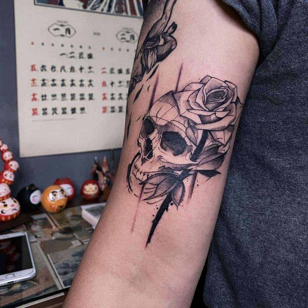 Tattoo of a skull and rose on a person's upper arm