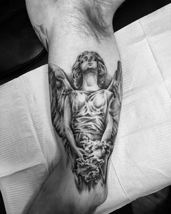 A detailed black and grey tattoo on the forearm featuring an angel holding a cloud, with soft shading and a serene, flowing pose.