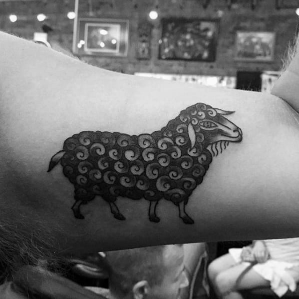 Black sheep tattoo with intricate curls on upper arm