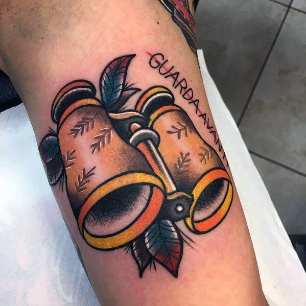Traditional-style binoculars tattoo with bold colors, leafy details, and the phrase 'Guarda Avanti,' symbolizing vision and looking ahead.