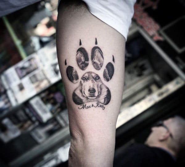 Siberian Husky tattoo on a man's arm, featuring a detailed paw print design with a realistic dog portrait inside and personalized text below.