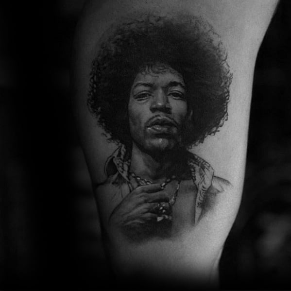 Black and gray tattoo of Jimi Hendrix, showcasing his iconic afro and charismatic expression