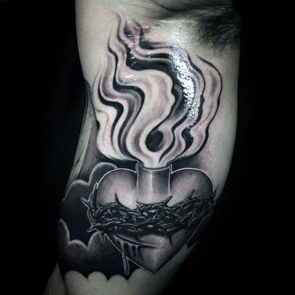 Black and grey 3D tattoo of a sacred heart wrapped in thorns, emitting flames, with bold shading creating a dramatic and spiritual design.