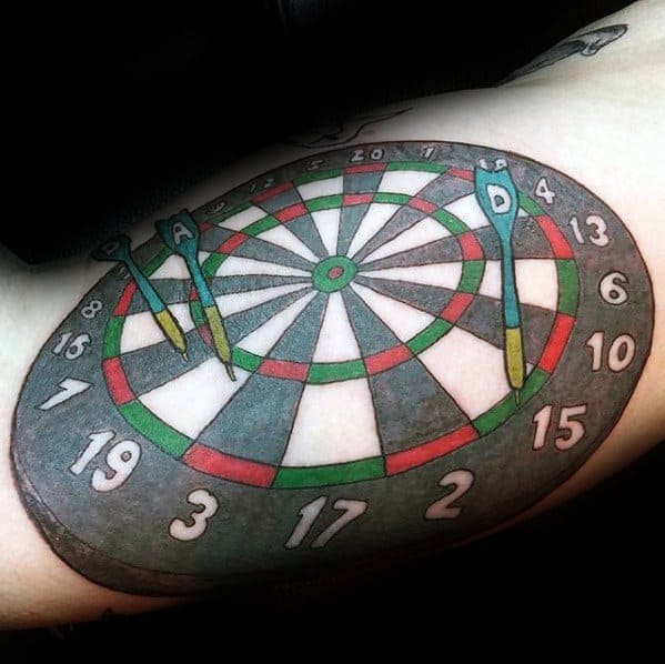 Color tattoo of a full dartboard with three darts labeled A, D, and P, highlighting a personalized and playful tribute to the game.