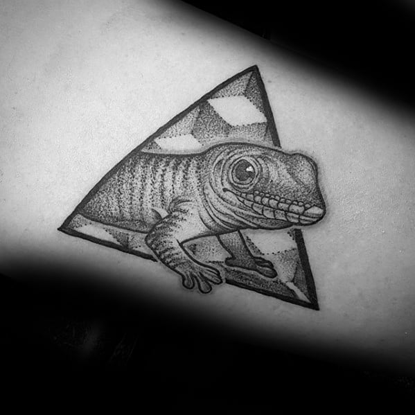 Gecko tattoo peeking out of a shaded triangle, with fine dotwork details and a playful, realistic expression.