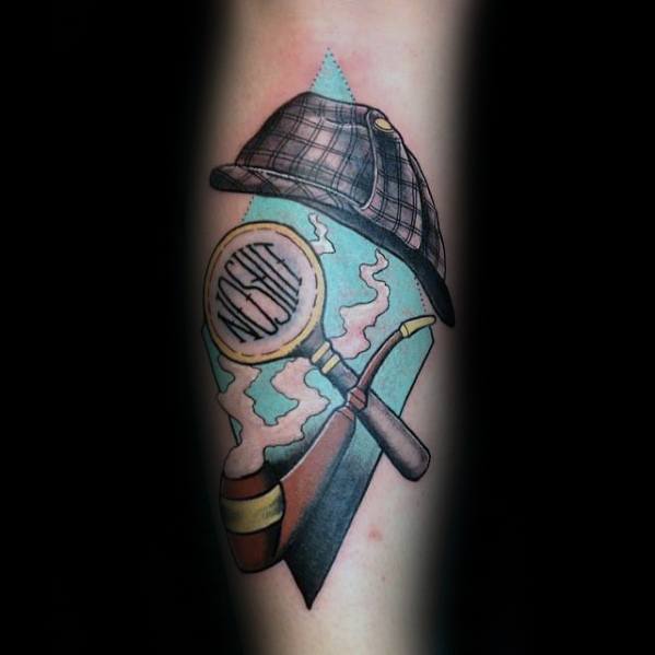 Colorful tattoo featuring Sherlock Holmes' signature deerstalker hat, a magnifying glass with visible fingerprints, and a smoking pipe with swirling smoke