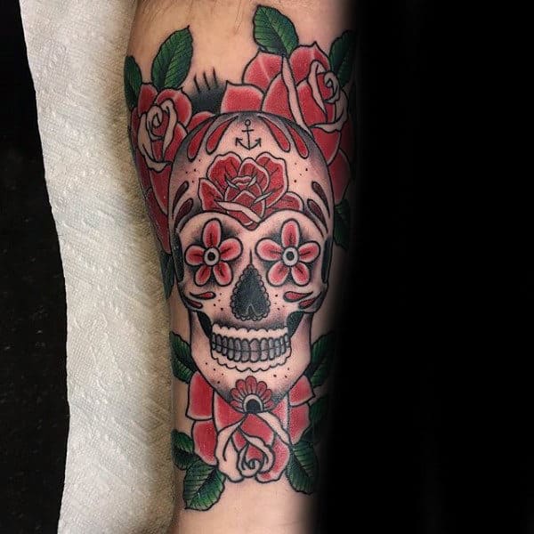 Tattoo of a skull with roses and floral designs surrounded by red and green colors